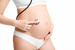 беременная девушка слушает ребенка стетоскопом
