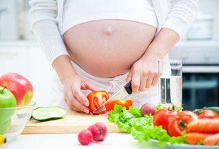беременная девушка режет помидоры