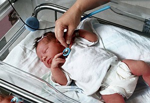 врач слушает новорожденного ребенка