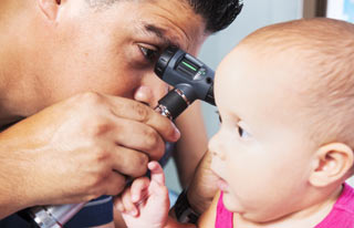 врач смотрит у ребенка ухо